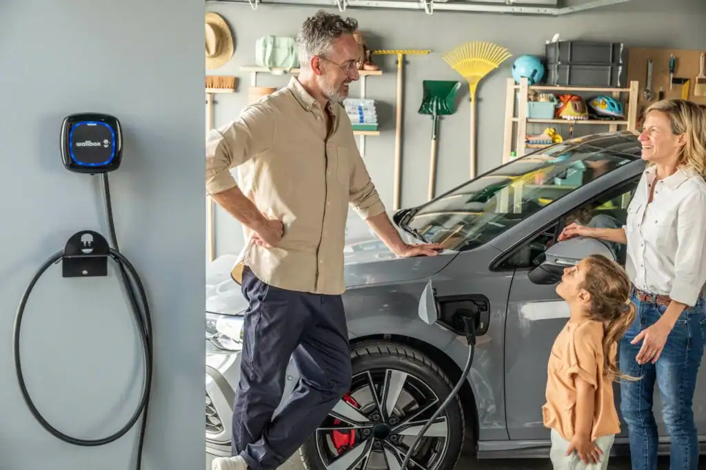 szaldó elszámolás (4) Család egy elektromos autót tölt a garázsban, miközben a napelemes rendszer által megtermelt energiát éves szaldó elszámolás szerint használják fel. A szaldó rendszerben a hálózatba betáplált áram és a vételezett mennyiség alapján történik az elszámolás, amely a háztartási méretű HMKE rendszerek esetén különösen fontos a felhasználónak.